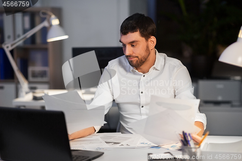 Image of businessman with papers working at night office