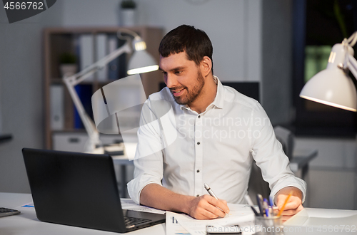 Image of businessman with laptop working at night office