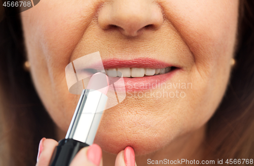 Image of close up of senior woman applying lipstick