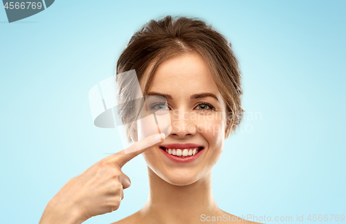 Image of beautiful young woman pointing to her nose