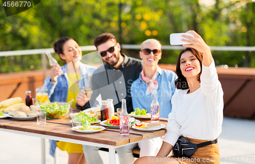 Image of happy friends taking selfie at rooftop party