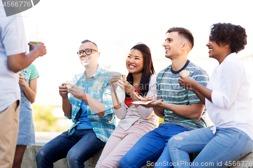 Image of friends eating pizza and sandwiches in park