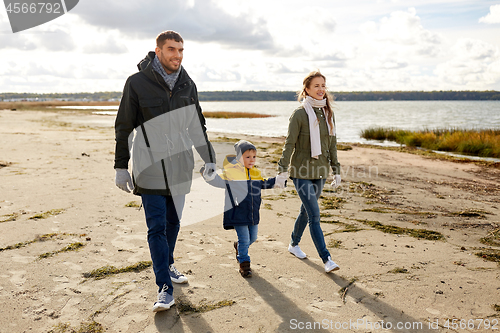 Image of happy family walking along autumn beach