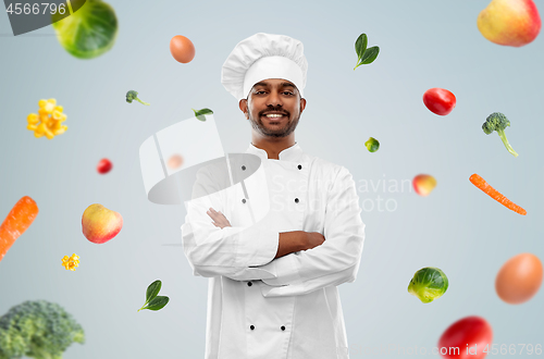 Image of happy male indian chef in toque over vegetables