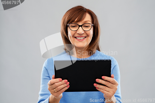 Image of senior woman in glasses using tablet computer