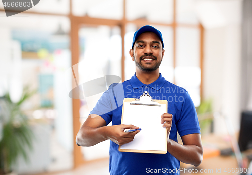 Image of happy indian delivery man with clipboard at office