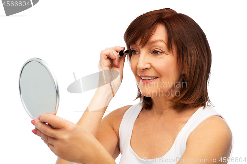 Image of smiling senior woman with mirror applying mascara