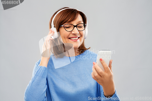 Image of senior woman in headphones listening music on cell