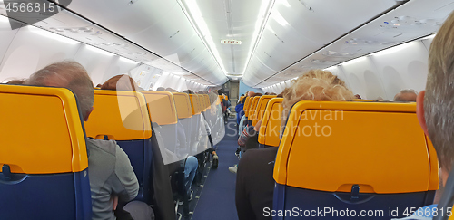 Image of People are sitting in an airplane cabin during flight
