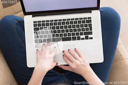 Image of young woman on sofa at home websurfing