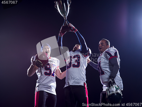 Image of american football team with trophy celebrating victory