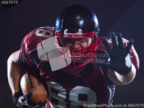 Image of American football player holding ball while running on field