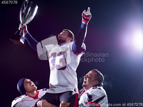 Image of american football team with trophy celebrating victory