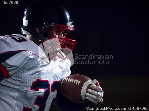 Image of American football player holding ball while running on field