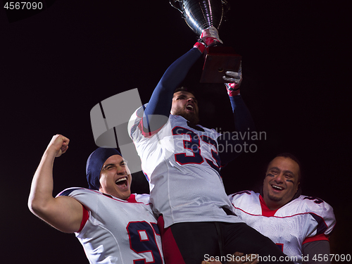 Image of american football team with trophy celebrating victory