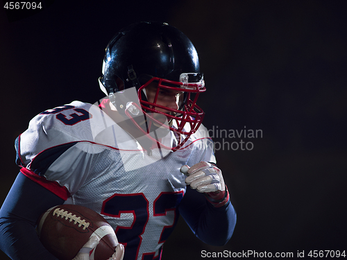 Image of American football player holding ball while running on field