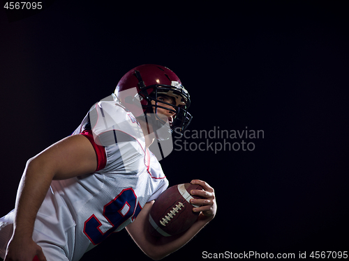 Image of American football player holding ball while running on field