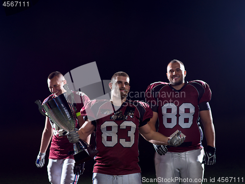 Image of american football team with trophy celebrating victory