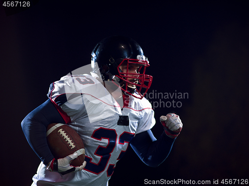 Image of American football player holding ball while running on field