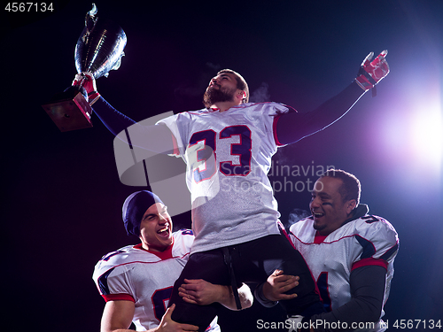 Image of american football team with trophy celebrating victory