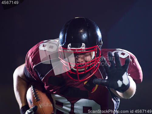 Image of American football player holding ball while running on field