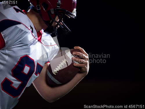 Image of American football player holding ball while running on field