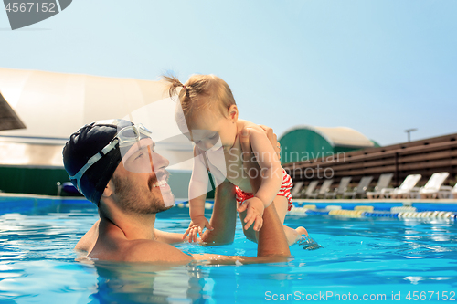 Image of Happy family having fun by the swimming pool