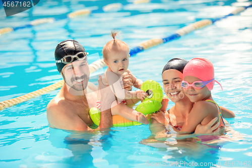 Image of Happy family having fun by the swimming pool