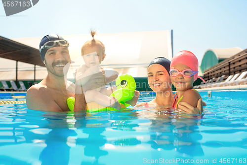 Image of Happy family having fun by the swimming pool