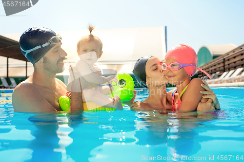 Image of Happy family having fun by the swimming pool