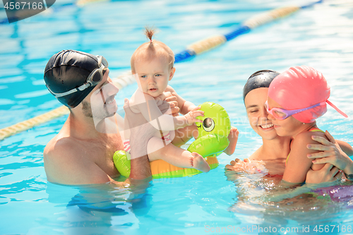 Image of Happy family having fun by the swimming pool