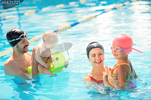 Image of Happy family having fun by the swimming pool