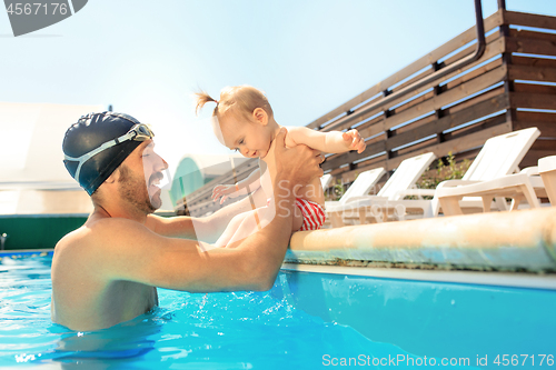 Image of Happy family having fun by the swimming pool