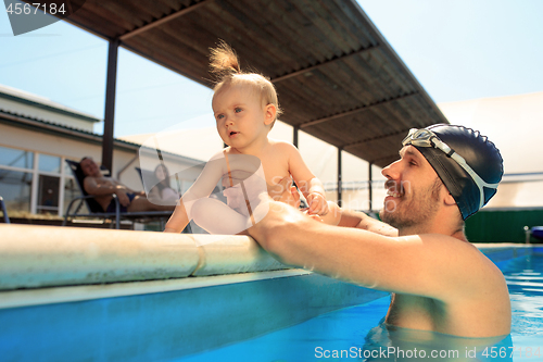 Image of Happy family having fun by the swimming pool