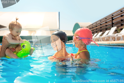 Image of Happy family having fun by the swimming pool