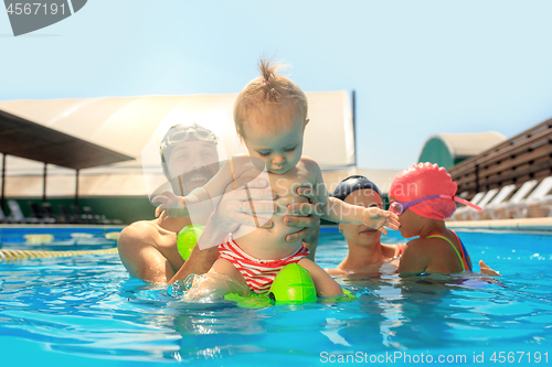 Image of Happy family having fun by the swimming pool