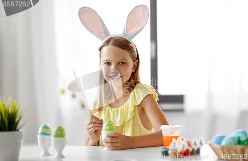 Image of happy girl coloring easter eggs at home