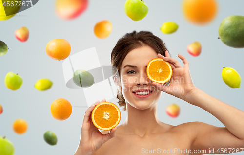 Image of smiling woman with oranges over fruits background