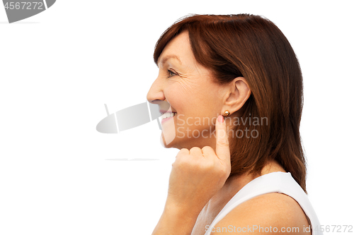 Image of smiling senior woman pointing to her earring