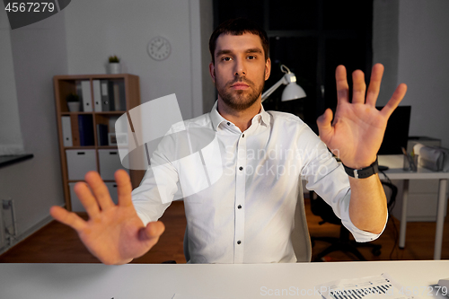 Image of businessman using gestures at night office