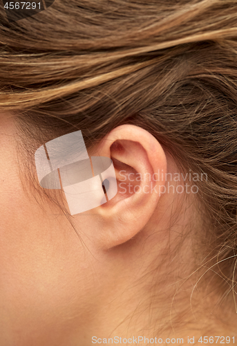 Image of close up of young woman pointing finger to her ear