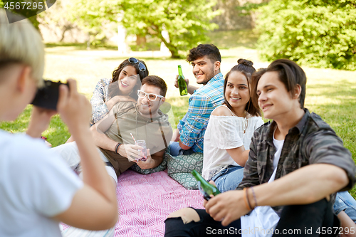 Image of friends with drinks photographing at summer picnic