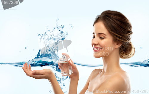 Image of happy woman with perfume over water splash