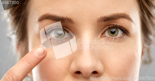 Image of close up of woman pointin finger to eye