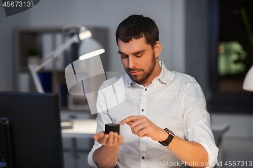 Image of businessman using smart speaker at night office