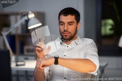 Image of businessman using smart watch at nigh office