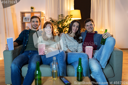 Image of friends with beer and popcorn watching tv at home