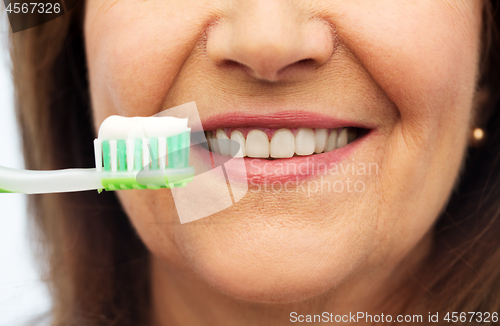 Image of senior woman with toothbrush brushing her teeth