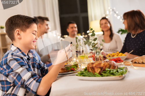 Image of boy with smartphone at family dinner party