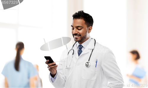 Image of smiling indian male doctor with smartphone